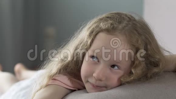 快乐的孩子躺在沙发上微笑着用爱看着她的父母视频的预览图