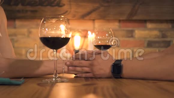 浪漫的一对夫妇手拿蜡烛和酒杯在桌子上男人和女人牵手浪漫的约会视频的预览图