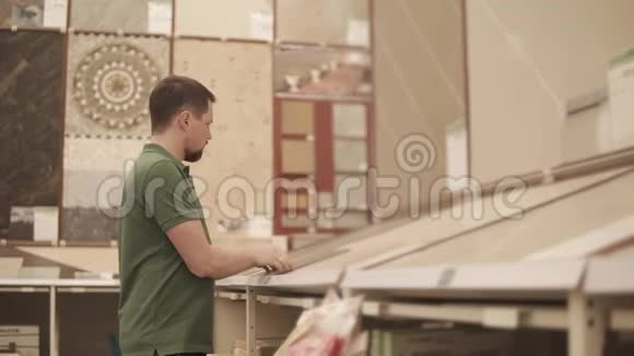 男购物者正在一家建筑商店里看瓷砖视频的预览图