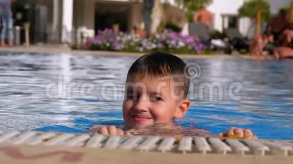 快乐的男孩带着鳍在一个有蓝色水的游泳池里游泳慢动作视频的预览图