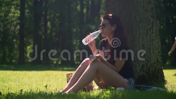 年轻女子从公园的瓶子里喝水视频的预览图
