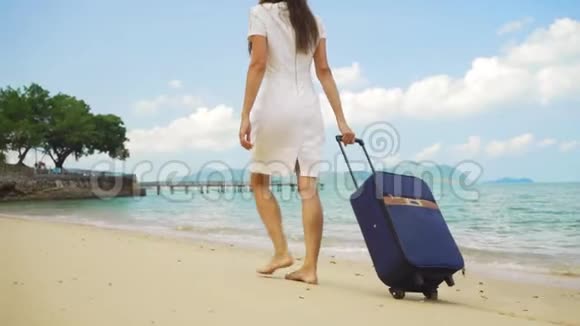 商务女性带着一个手提箱沿着美丽的大海的海岸散步自由职业概念期待已久的休闲概念视频的预览图