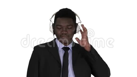 戴着耳机的英俊的美国黑人商人正在听白色背景的音乐视频的预览图
