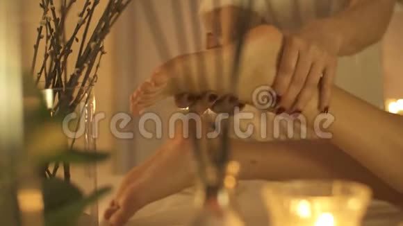 年轻女子在美容院做脚部按摩关门蜡烛背景视频的预览图