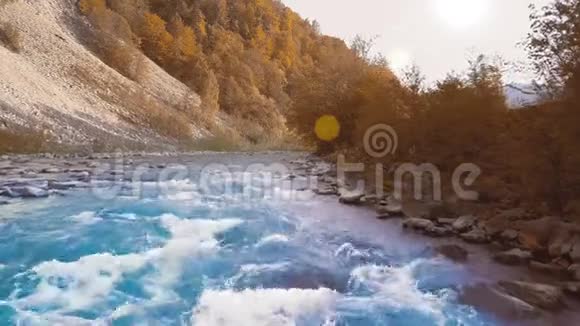 低速飞过奔流的山河青翠在山间日落时间太阳射线发出橙色的耀斑视频的预览图