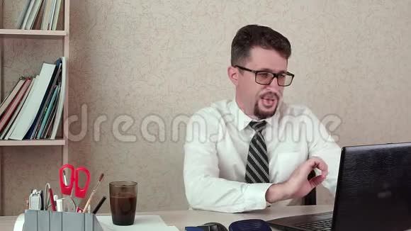 带着胡子和眼镜的男办公室经理为笔记本电脑喝咖啡视频的预览图