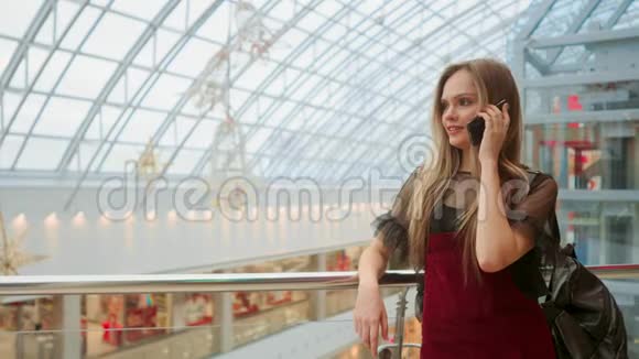 销售消费主义年轻女性手拿智能手机和购物袋站在购物中心附近聊天视频的预览图