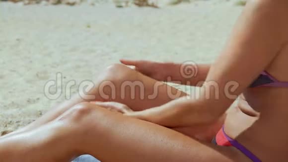 穿着泳衣的女人在海边的皮肤晒黑剂中摩擦视频的预览图