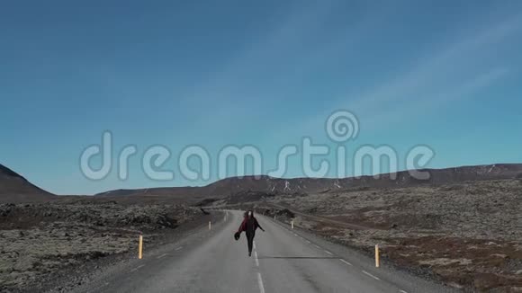 女孩在冰岛的一条空路上奔跑视频的预览图