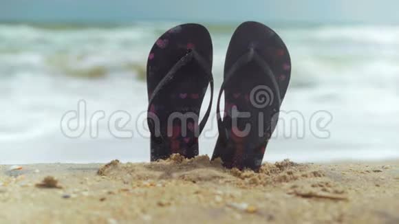 特写镜头沙滩拖鞋粘在沙滩上的沙滩上冲着沙滩浪冲视频的预览图