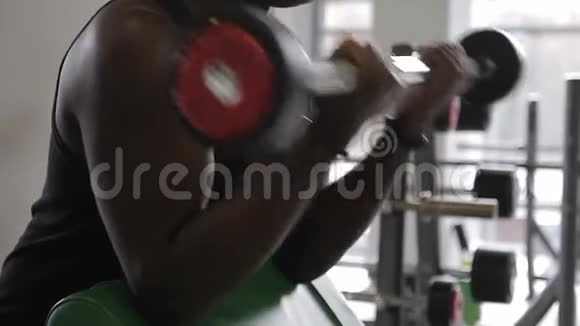 这位美国黑人运动员在现代健身房的斜凳旁站着杠铃前面视频的预览图