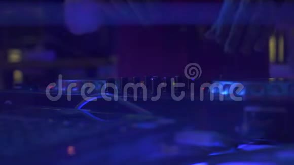 DJ手在音响控制台用于混合舞蹈音乐和迪斯科俱乐部的彩色灯光DJ调音台和音乐控制台视频的预览图