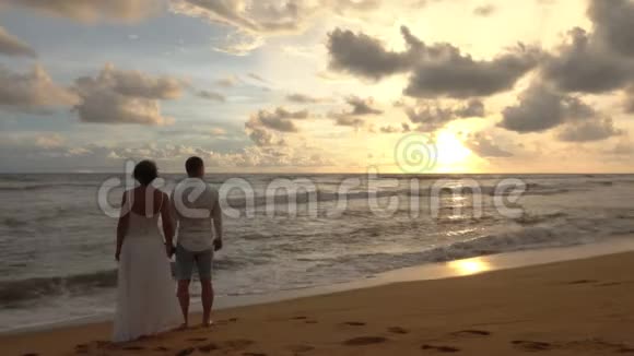 年轻的情侣在浪漫的约会中遇到海滩上的日落手牵手视频的预览图