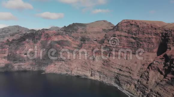 空中射击巨大的黑红色火山岩是海洋蓝色水域中的一座山对着蓝天加那利视频的预览图