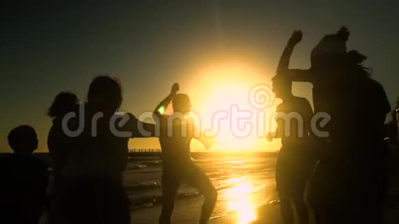 欢乐的人群在海滩上跳舞他们在阳光下跳跃人们玩得很开心他们很开心人的剪影视频的预览图