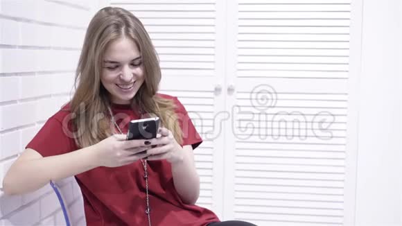 穿着红色T恤的年轻女子发短信微笑着视频的预览图