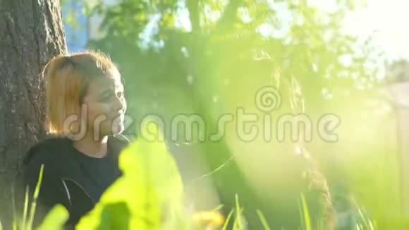 女孩和她的俄罗斯黑梗坐在一棵树附近的草地上抚摸它视频的预览图