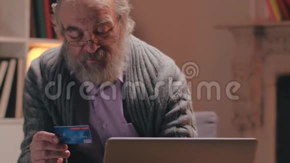 老年人将信用卡信息输入笔记本电脑以支付公用事业费视频的预览图