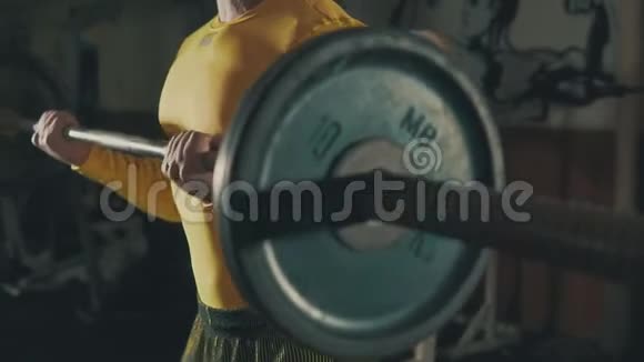 肌肉男在阴暗的健身房里用杠铃做二头肌运动视频的预览图