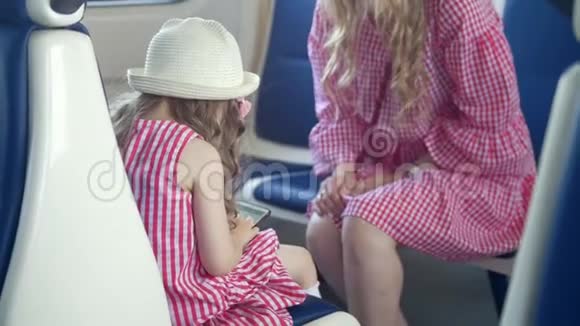 小女孩的后视图使用智能手机坐在火车上母亲面前的扶手椅上视频的预览图