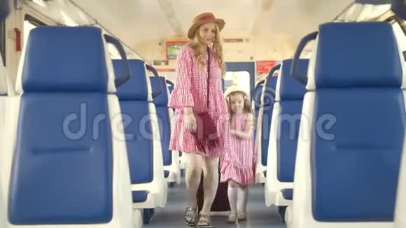 可爱的小女孩和她的妈妈走进火车车厢到他们的座位上视频的预览图