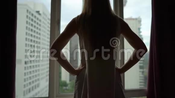 在市中心的公寓里一位成功的富有的年轻女子站在窗户旁全景尽收眼底视频的预览图