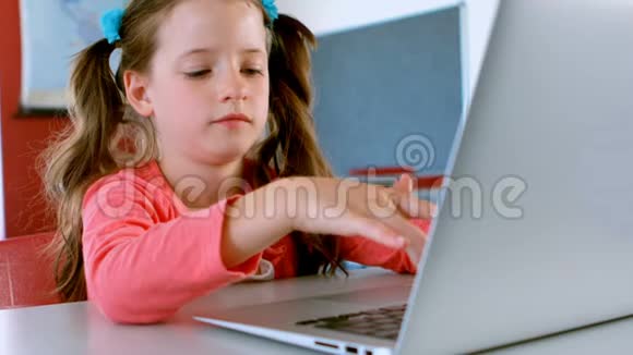 可爱的高加索女学生坐在办公桌前在教室里使用笔记本电脑视频的预览图