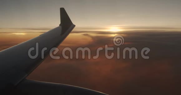 一架飞机的机翼在云层上方飞行天空是夕阳从平面的窗口查看视频的预览图