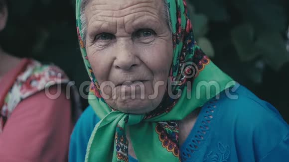 户外花园里一个戴着围巾的老妇人的画像视频的预览图