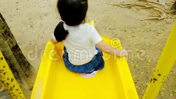下午一个女孩独自在公园里玩黄色滑梯雨后她快乐地玩着视频的预览图