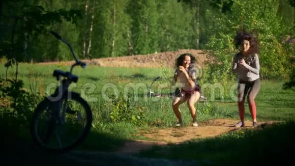 跳跃和蹲下年轻女孩骑自行车在树林里玩运动阳光明媚的一天视频的预览图