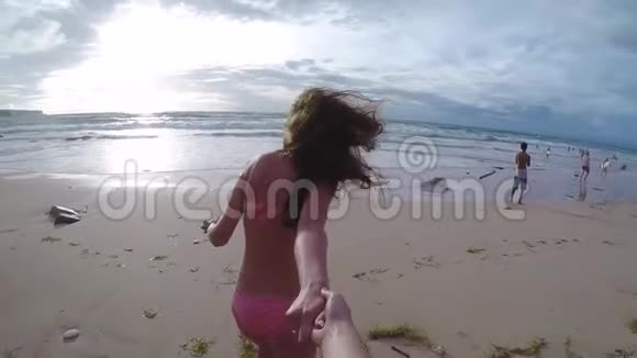 FPV美丽的女孩手牵着手在巴厘岛日落时分沿着沙滩奔向大海慢动作视频的预览图