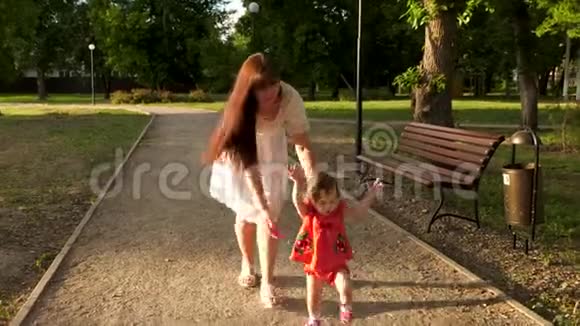 妈妈在公园里的小路上看到了一个学会走路和微笑的小宝宝视频的预览图