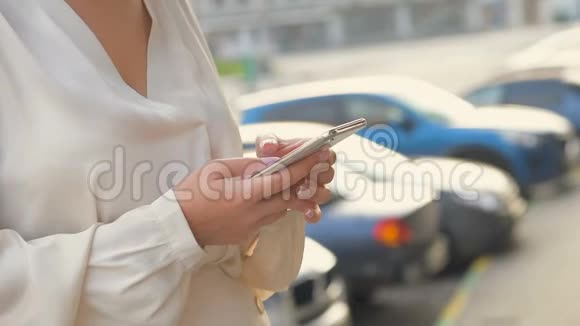 在一个城市里当一个年轻的女人在户外使用她的智能手机时她的手慢动作视频的预览图
