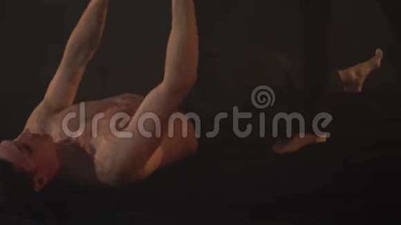 一个男人躺在地板上举起一个纤细的女人做一根绳子视频的预览图
