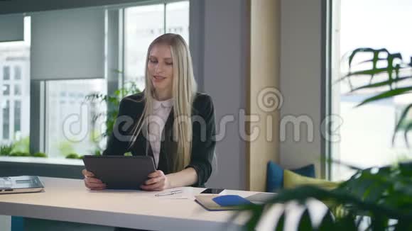时尚的商务女性办公室里有平板电脑优雅的女士西装革履端着笔记本电脑和冲浪平板电脑坐在桌上视频的预览图