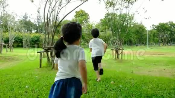 一个男孩和一个女孩在公园里玩耍他们在下午快乐地穿过公园视频的预览图