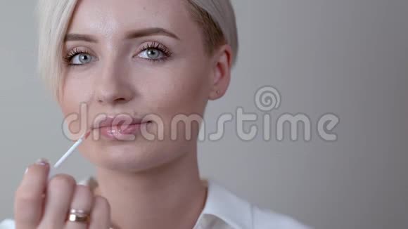 一个可爱的短发金发女孩用魔杖涂上唇彩视频的预览图