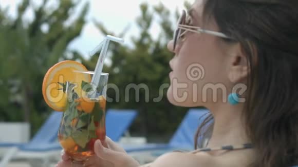 坐在豪华豪宅池边享受清凉鸡尾酒的女孩视频的预览图