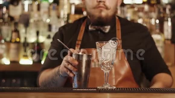 酒保正在将混合饮料过滤到玻璃杯中以便上桌特写他的手视频的预览图