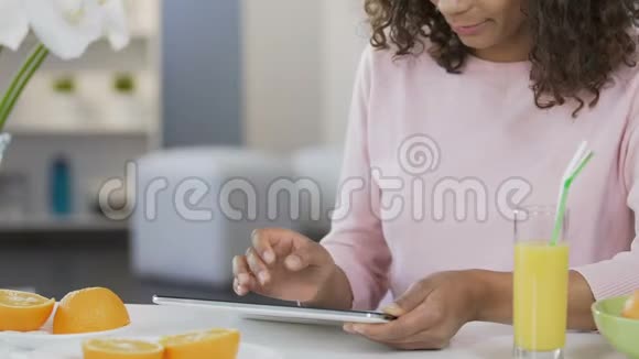 网上购物在厨房的平板电脑上滚动着一个漂亮的混血女人视频的预览图