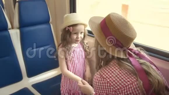 可爱的小女孩和她的妈妈一起旅行牵着手在靠近窗户的火车上交谈视频的预览图