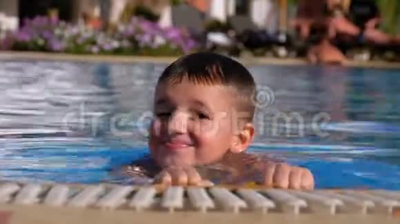 快乐男孩与拖鞋游泳在游泳池与蓝水视频的预览图