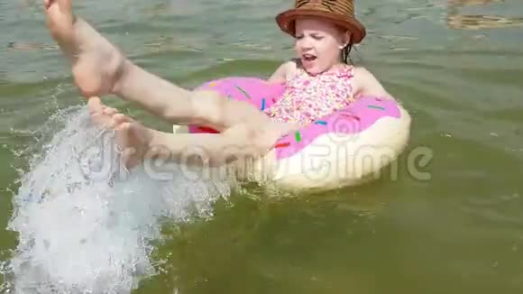 孩子在充气圈一个快乐的女孩在海里的一个充气圈里飞溅视频的预览图