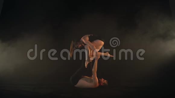 一个长着细长腿的男人把一个优雅的女人抱在空中支撑着杂技瑜伽慢动作视频的预览图