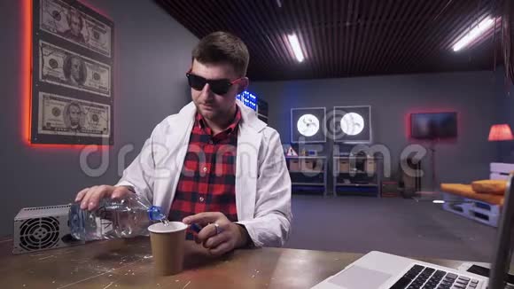 穿着白色实验外套的可爱男人把水从塑料瓶倒入纸杯视频的预览图