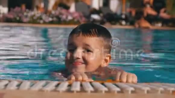 快乐男孩与拖鞋游泳在游泳池与蓝水视频的预览图