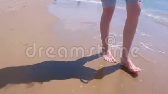赤脚女游客在海边沙滩水中散步双腿特写视频的预览图