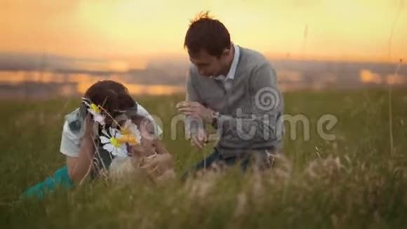 爸爸妈妈和儿子一起玩宝宝拿着玩具坐在草地上夏天晚上在大自然中视频的预览图