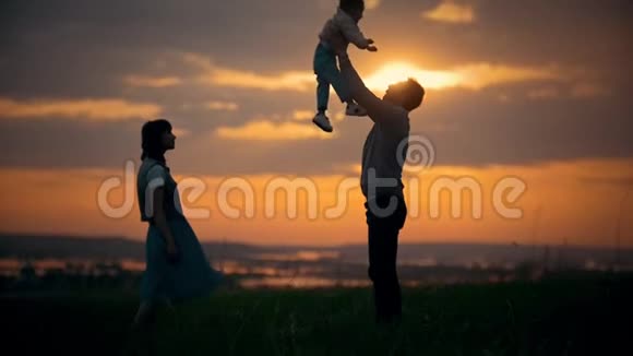 一家人站在夕阳的背景上父亲把儿子抛在空中一个夏日的傍晚视频的预览图